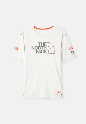 T-shirt blanc à manches courtes avec le logo "THE NORTH FACE" en gris. Présente un tissu texturé, des accents orange et un petit graphisme sur l'ourlet.