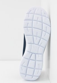 Semelle de chaussure en caoutchouc blanc texturé, avec de profondes rainures pour l'adhérence ; le côté présente un dessus en maille bleu foncé pour une meilleure respirabilité.