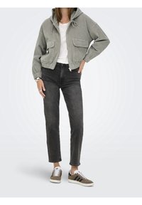 Szara kurtka ze sztruksu z kapturem, przednie kieszenie, pod spodem biała koszula, czarne jeansy oraz brązowo-białe trampki z czarnymi paskami.