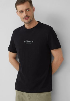Schwarzes Baumwoll-T-Shirt mit kurzen Ärmeln und rundem Ausschnitt. Auf der Brust befindet sich ein dezentes s.Oliver Co. Logo in Grau, gegründet 1980.