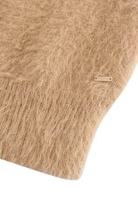 Beige texturerad matta med en mjuk, fluffig yta, med en slät kant och en liten metallbricka fäst.