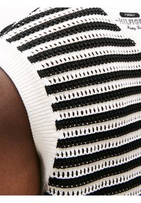 Biały i czarny dziergany top bez rękawów z poziomymi paskami, z teksturowanym wzorem i prążkowanym dekoltem.
