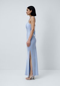 Ljusblå satin maxiklänning med figursydd bodice, tunna axelband och sidofrack. Klänningen har en knytdetalj i ryggen och en mjuk textur.