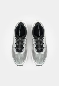 Chaussures de course légères en gris et blanc, avec une tige en maille texturée, des lacets noirs et un design élégant avec une semelle en caoutchouc prononcée.