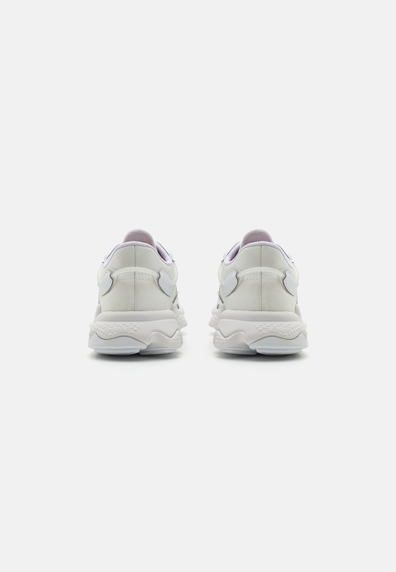 Para białych sportowych sneakersów z grubymi podeszwami, przedstawionych od tyłu na jednolitym białym tle.