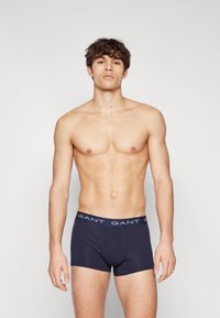 Marineblå boxertruser med en myk tekstur, med en GANT-logo på midjebåndet. Designet er tettsittende og gir komfort og støtte.