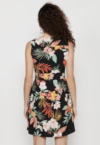 Vestido negro sin mangas con un vibrante patrón floral en tonos blancos, rosas, naranjas y verdes. La tela tiene una textura suave.