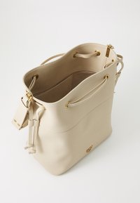 Svetlobéžová kožená kabelka v tvare vedra s textúrovaným povrchom, so sťahovacou šnúrkou, zlatým kovovým doplnkom a priestranným vnútrom.