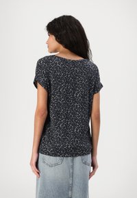 Black and gray leopard print short-sleeve t-shirt, soft fabric, curved hem, relaxed fit, paired with a light blue denim skirt.