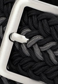 Czarny i szary pleciony pasek z tkaniny z metalową, srebrną kwadratową klamrą i detalami w postaci przeszyć, ukazujący teksturę i splątane wzory.