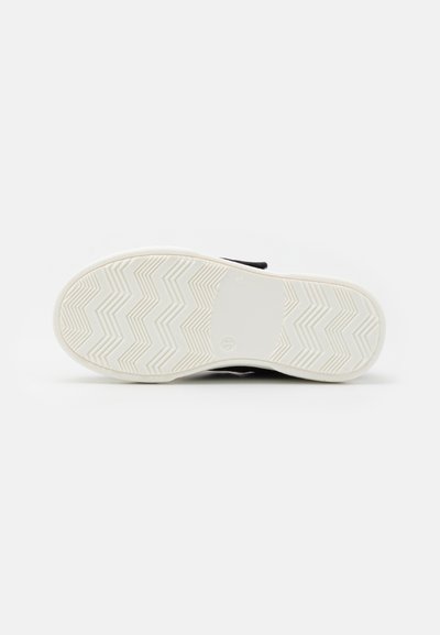 La suola della scarpa presenta una base in gomma bianca con un motivo a zigzag per una migliore aderenza. Il materiale superiore è di colore nero ed è progettato per comfort e flessibilità.