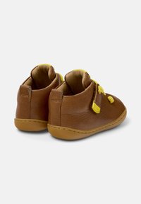 Chaussures pour tout-petits en cuir marron avec des lacets jaunes, de forme arrondie et une semelle souple. Présentent une languette à l'arrière pour un enfilage facile, avec des détails cousus.