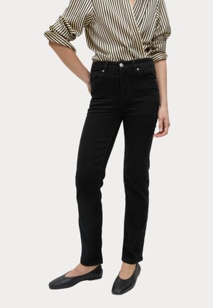 Czarne, wąskie dżinsy o gładkiej fakturze, wysoki stan i pięć kieszeni, połączone z bluzką w paski oraz płaskimi butami.