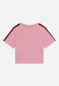 Majica s kratkimi rokavi z enotno roza barvo in maroon poudarnimi črtami na ramenih. Mehak material z sproščenim fitom.