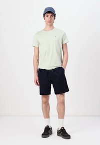 Lysegrønn bomull t-skjorte, marineblå shorts, mørke sneakers, hvite sokker, og en blå caps. Enkelt design uten bemerkelsesverdige mønstre.