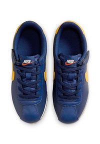 Baskets de sport bleu marine avec des accents jaunes, fabriquées en matériau synthétique. Les caractéristiques incluent une semelle extérieure texturée, des lacets et un logo sur la languette.