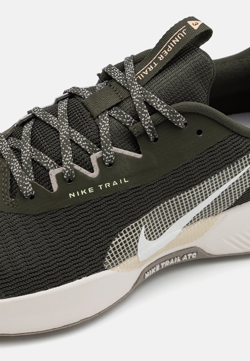 Baskets Nike Trail en vert foncé avec un dessus en maille texturée, des lacets réfléchissants et un détail en swoosh blanc. Légères et conçues pour la course en pleine nature.