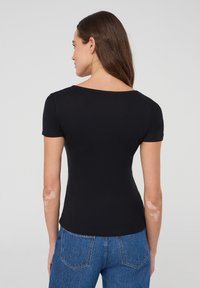 T-shirt nera a maniche corte con un design semplice, realizzata in tessuto morbido. Presenta un colletto rotondo e una vestibilità slim.