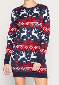 Robe pull de Noël bleu marine avec des rennes blancs, des cœurs rouges, des flocons de neige, des sapins de Noël et le texte « Joyeux Noël ! » en rouge.