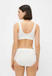 Hvit bomullsbralette og høy midje truse-sett. Begge delene har et enkelt design og myk tekstur, med brede stropper og sømløs finish.