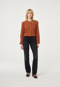 Gebrande sinaasappel ribgebreide cardigan met gouden knopen, gecombineerd met hooggelegen zwarte rechtvaardige jeans en glanzende donkerbruin hakken.