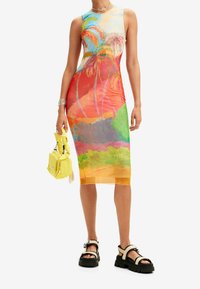 Farverig ærmeløs kjole med et tropisk print af palmer, i nuancer af orange, pink, grøn og gul, lavet af strækbart materiale.