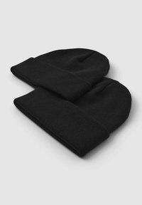 Cappelli beanie neri lavorati a maglia impilati uno sopra l'altro, con un bordo spesso ripiegato e una texture morbida e liscia.