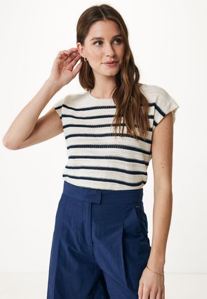 Haut tricot à rayures en crème et bleu marine, avec des manches courtes et un col rond, associé à un pantalon large bleu marine.
