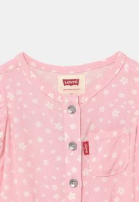 Ljusrosa kortärmad skjorta med vitt blommönster, knäppa fram, och bröstficka. Har silverfärgade knappar och märkesetikett.