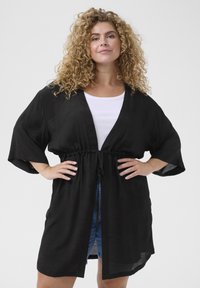 Musta kimono-tyylinen kardigan, jossa on vyötärölle kiristetty malli, lyhyet hihat ja kevytra rakenteet. Varustettu syvällä V-puoleisella kaula-aukolla ja avoimella etuosalla.