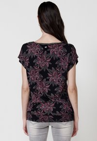 Haut noir avec un motif floral en rouge et gris. Manches courtes, encolure ronde avec une finition décorative, et coupe ample et décontractée.