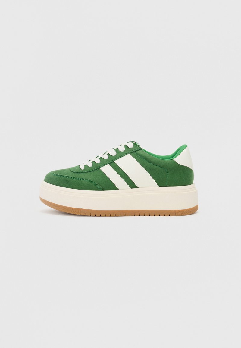 Tenis verde cu dungi albe, realizat din material textil. Dispune de o talpă platformă cu bază din cauciuc și guler căptușit pentru confort.