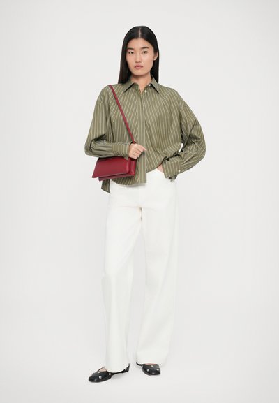 Olive green striped shirt with buttons, white wide-leg pants, and a red handbag. Black flats with embellishments complete the outfit.