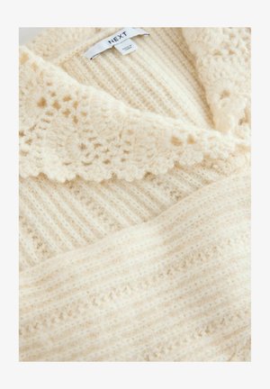 Kermainen neulepusero, jossa on teksturoitu kuvio, liehuva kaulus ja pinnan juovat. Pehmeä, pörröinen materiaali, joka näyttää mukavalta.