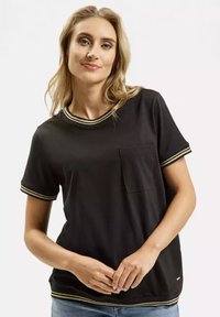 Czarna koszulka z krótkimi rękawami, złotymi paskami przy kołnierzyku i mankietach oraz kieszenią po lewej stronie. Wykonana z gładkiego materiału.
