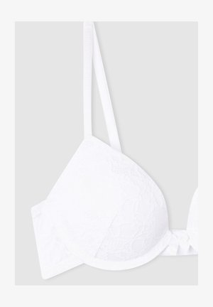 Reggiseno bianco in pizzo con coppe imbottite, spalline regolabili e dettaglio a fiocco al centro. Texture liscia e motivo floreale su tutta la superficie.