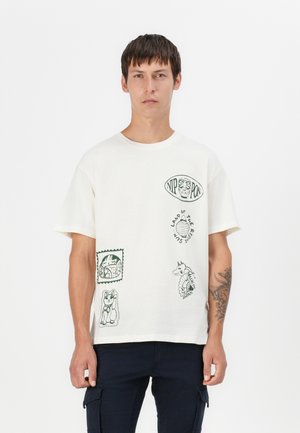 Witte katoenen T-shirt met groene gedrukte grafieken, inclusief dieren en tekstaccenten. Korte mouwen en een ronde hals.