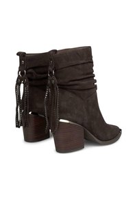 Botas de tobillo de ante marrón con un diseño arrugado, acentos de borlas y tacones de madera apilados. Presentan una puntera redondeada y detalles metálicos.