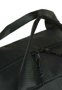 Bolso negro con tejido de nailon texturizado, cierre de cremallera y dos resistentes asas trenzadas. Presenta herrajes de cremallera en negro y acentos trenzados.