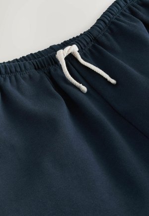 Marineblaue Jogginghose mit einem elastischen Bund und einem weißen Kordelzug. Glatte Textur mit sichtbaren Nähten entlang der Kanten.