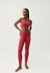Röd sportbh med en kortad design och matchande högmidjade leggings, med mjukt tyg och åtsittande silhuett.