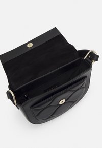 Borsa a mano in pelle nera con design trapuntato, ferrature dorate e patta magnetica. Interno in suede con tasca con zip ed etichetta del marchio.
