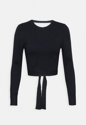 Suéter negro corto de tejido de punto acanalado, con mangas largas y un detalle atado en el frente. Cuello redondo simple.