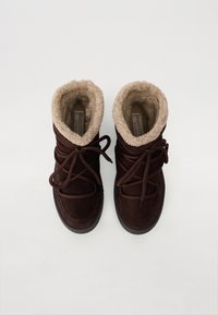 Bottes de cheville en cuir suédé marron avec une doublure beige en peluche, un design à lacets et une semelle en caoutchouc. Présente des coutures contrastées et une pointe arrondie.