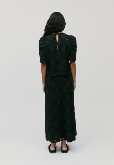 Abito nero in pizzo con maniche a palloncino e schiena con apertura a chiave, caratterizzato da un motivo a scacchi e una silhouette lunga e fluida.