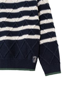 Maglione a maglia blu navy con strisce orizzontali bianche, motivo a diamante testurizzato, polsini a costine e un accento verde all'orlo. Patch del marchio visibile.