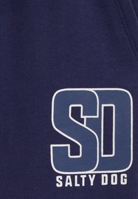 Temno modra tkanina vsebuje izrazit bel in svetloblue logo z črkami "SD" nad napisom "SALTY DOG" v beli barvi.