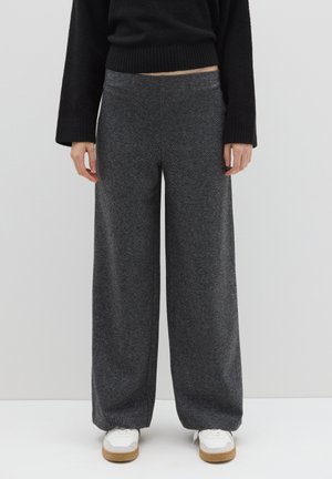 Pantalones de pierna ancha en tela gris oscuro con un acabado texturizado. Presentan una cintura alta y una pretina lisa. Combinados con zapatillas blancas.