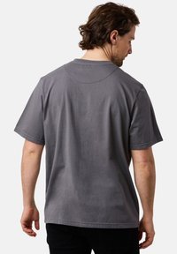 Harmaa puuvillapaita, jossa on lyhyet hihat, pyöreä kaula-aukko ja rento leikkaus, esitelty takaa, sileällä pinnalla.