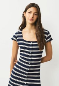 Námořnické a bílé pruhované šaty vyrobené z ribbového materiálu, s čtvercovým výstřihem, krátkými volánkovými rukávy a knoflíkovými Detaily po přední straně.